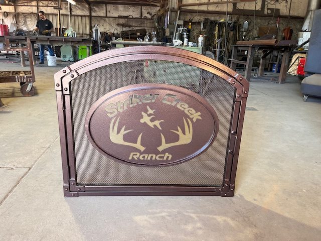 This door features a sturdy arched metal frame with fine mesh and a custom laser-cut emblem.