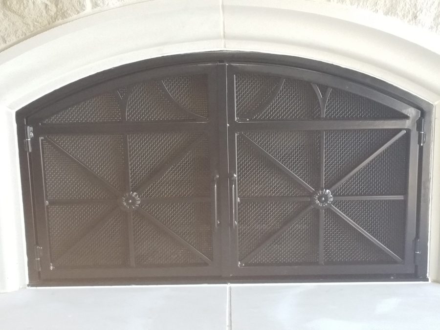 A black metal frame with symmetrical crossbars, decorative floral centerpieces, and a fine mesh backing.